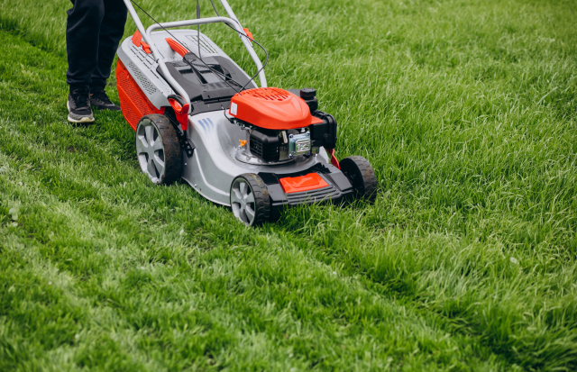 Clean Police Rasenmähen Rasenmäher schneidet grünes Gras auf einem gepflegten Rasen.