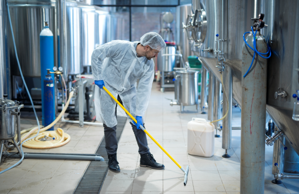 Clean Police Industriereinigung Mitarbeiter reinigt den Boden in einer modernen Produktionsanlage.